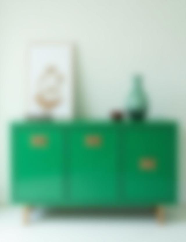 Aparador de diseño contemporáneo lacado en un vibrante verde esmeralda con tiradores de latón pulido, destacando en un ambiente minimalista.